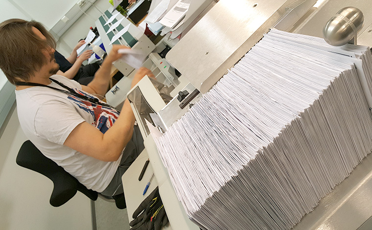 Kirjekuoria iso pino postinavauskoneen päädyssä.