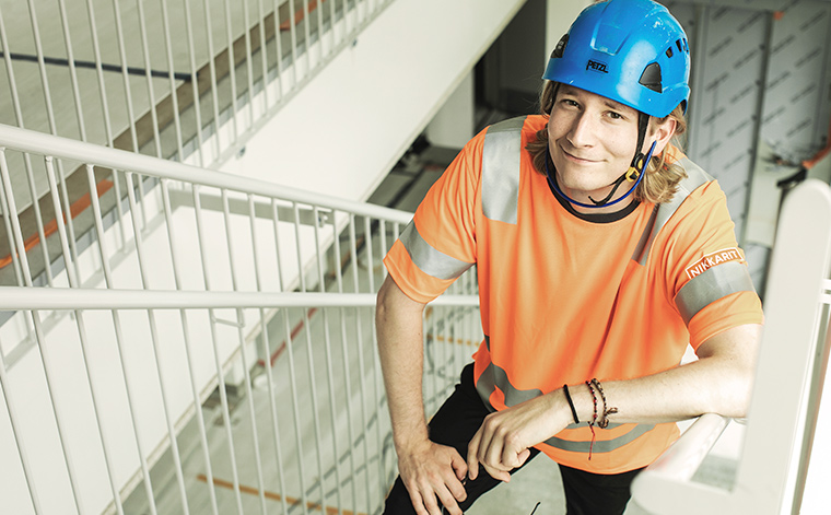 Nuori rakennusmies kiipeää portaita ylös.